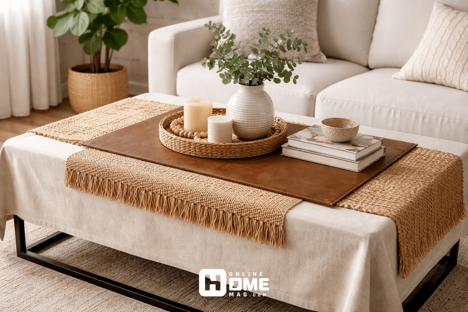 A coffee table with a large beige cotton tablecloth, layered with a natural jute runner and a leather mat on top. The setting has a modern and cozy vibe, with neutral colors blending together