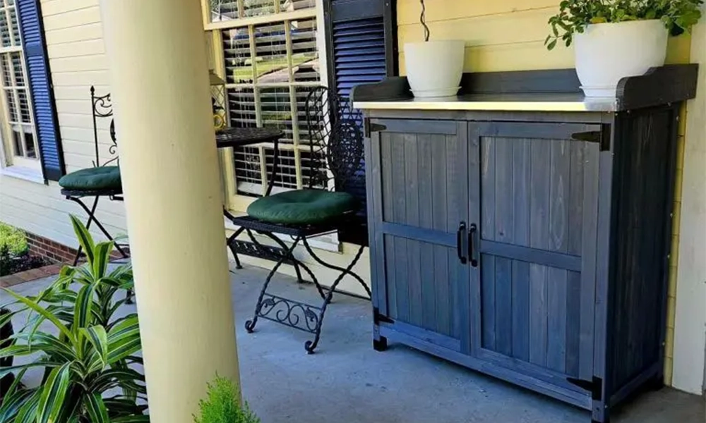 "Small patio with a wooden storage cabinet, two chairs, and plants, creating a compact and organized outdoor space.