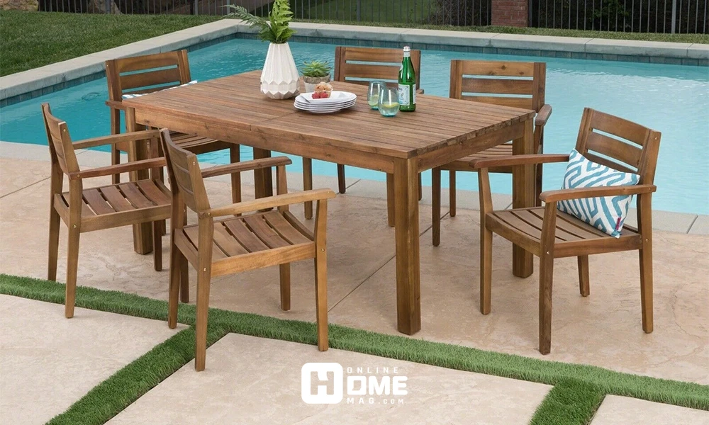 A simple wooden dining set placed outdoors by the pool, surrounded by green space.