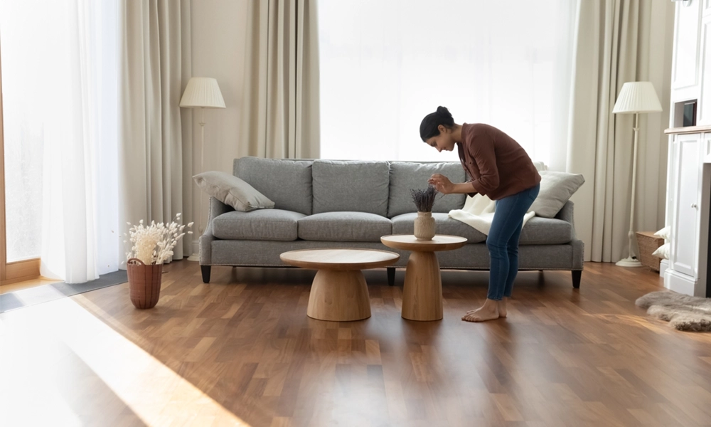 A person arranging flowers in a vase on a coffee table in a living room with a cozy and modern atmosphere.
